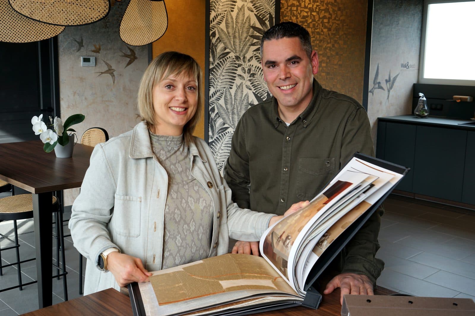 Delphine et Maxime Delallée, fondateurs de Maison Delallée, consultant un livre d'échantillons dans leur showroom